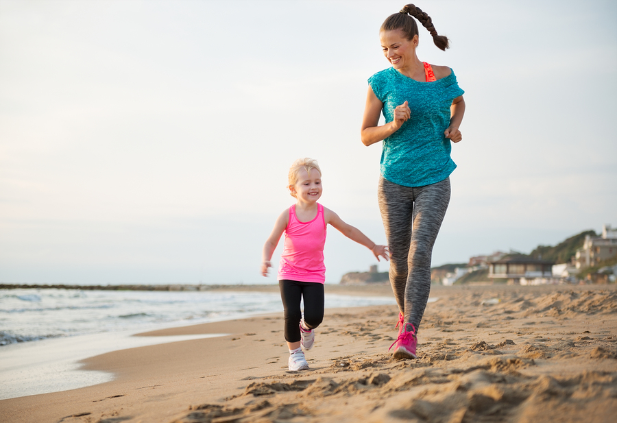 Healthy Mother And Baby Girl Running On Beach